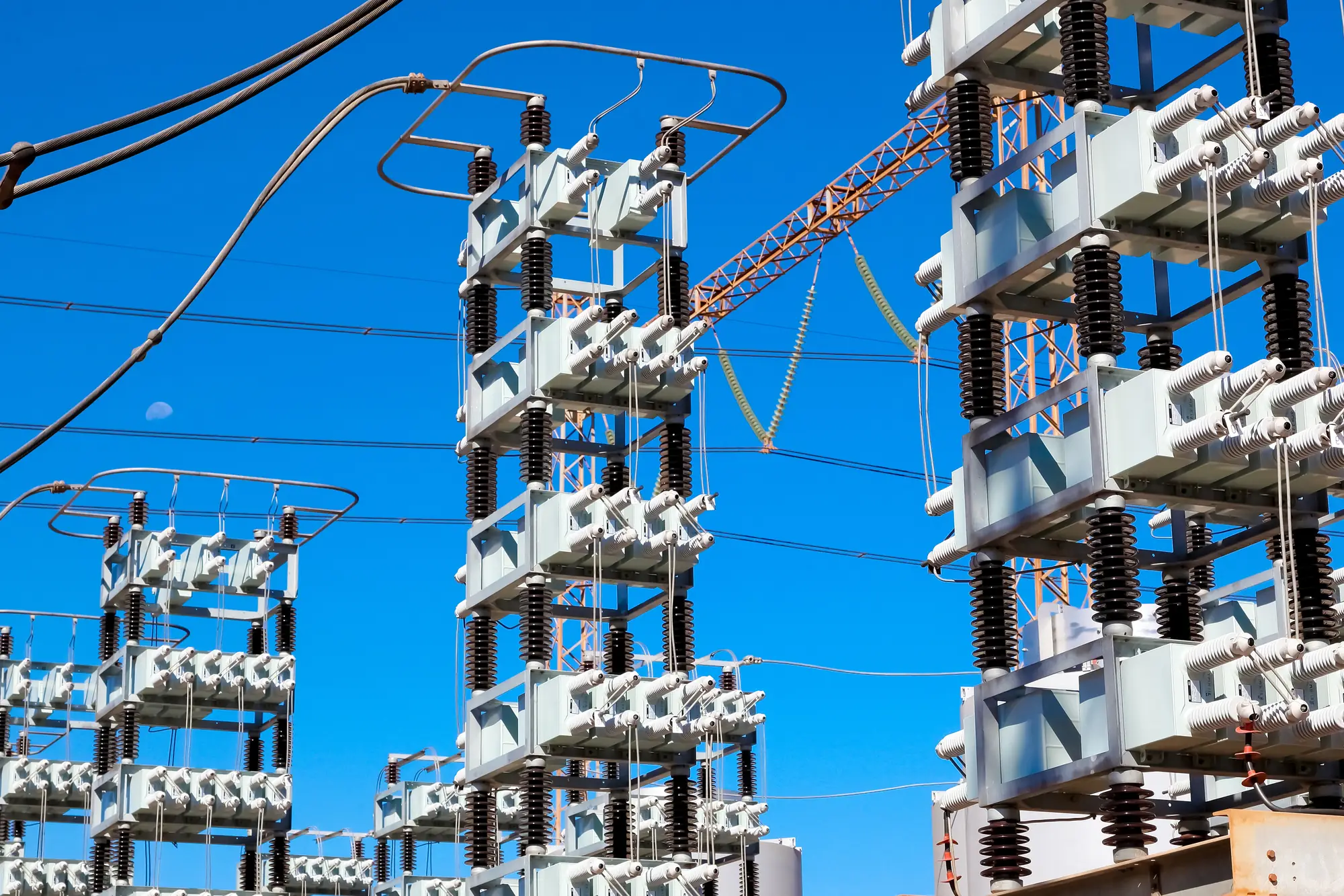 Electrical substation capacitor banks and insulator stacks against a clear blue sky